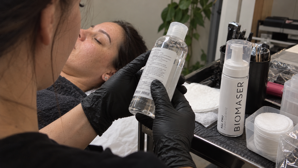 PMU artist checking the directions on a generic micellar water bottle before choosing a cleanser for the procedure