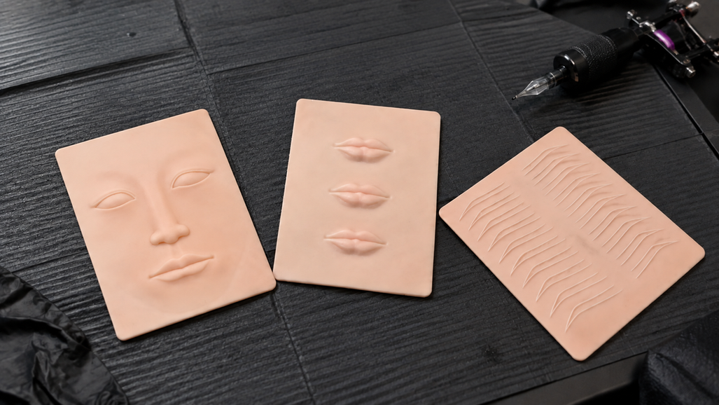 Face, lip, and eyebrow practice skins arranged on a tattoo workstation