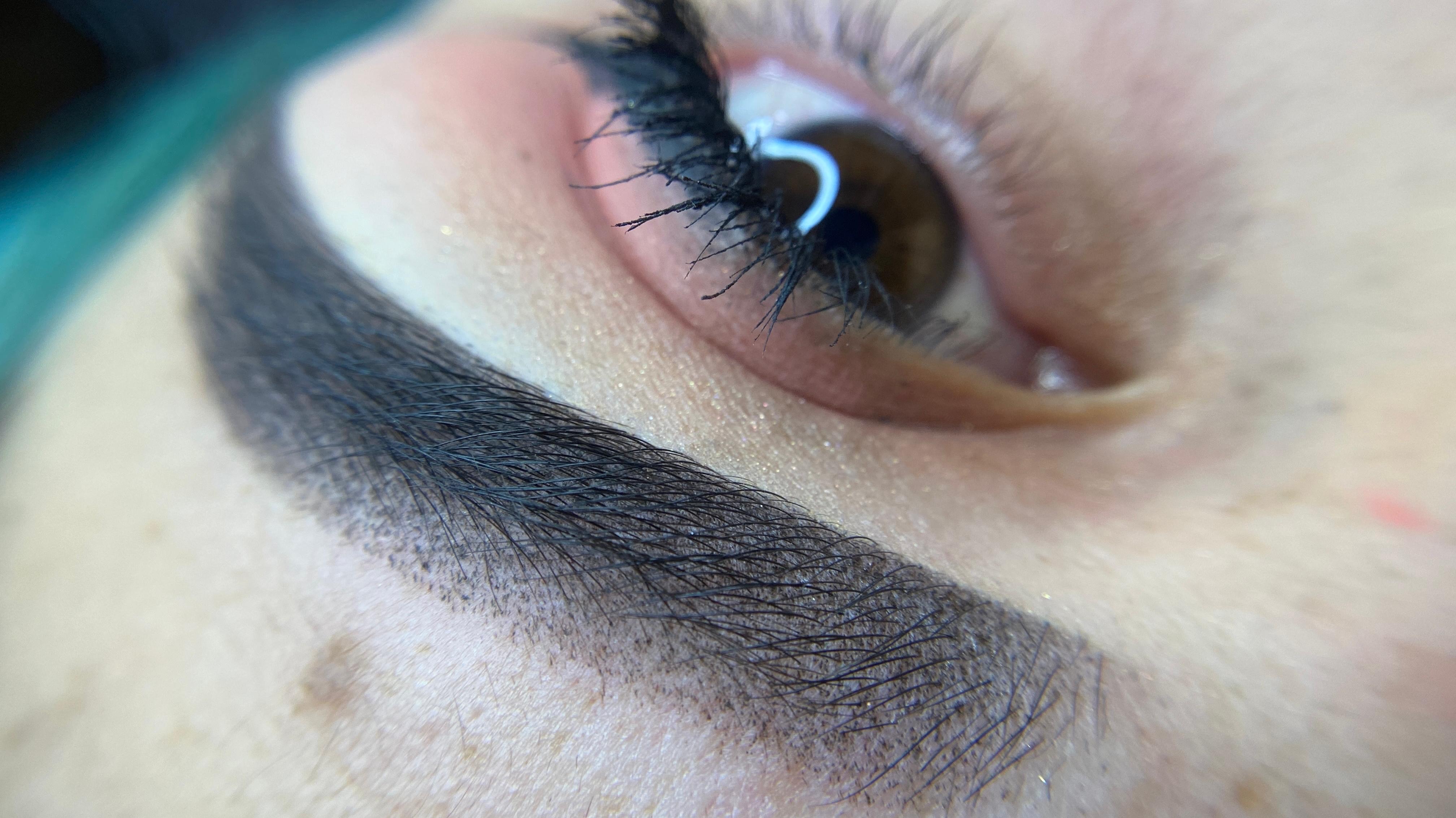 Close-up shot displaying the fine technique of microblading, showcasing natural-looking eyebrow strokes and detailed eye makeup.