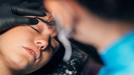 Technician applying Combo Brows treatment with precision tool for semi-permanent eyebrow enhancement.