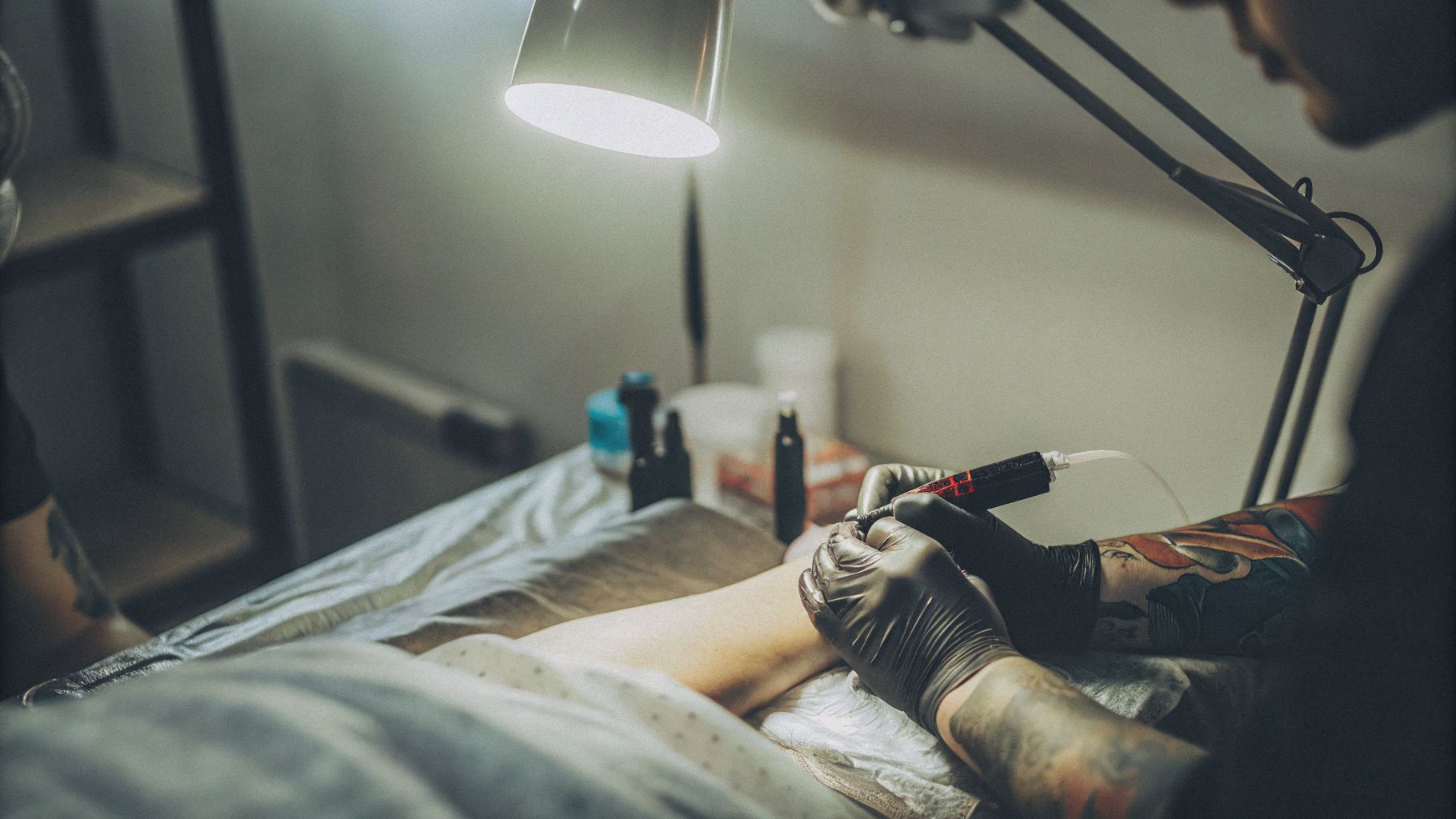 Professional tattoo artist applying ink in a hygienic studio environment