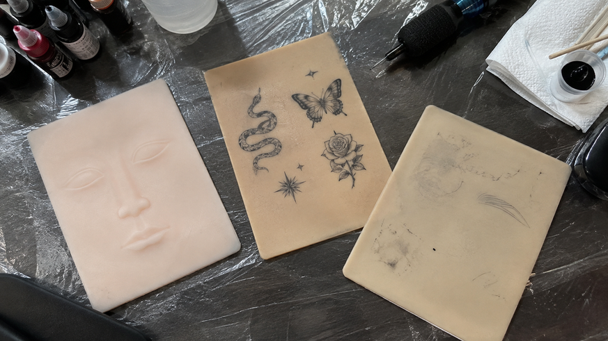 Three used practice skin sheets arranged on a tattoo workstation